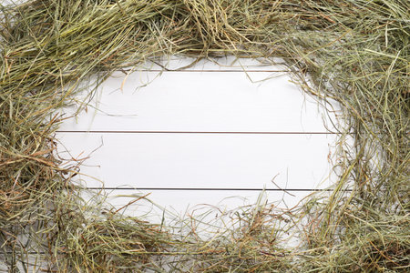 Frame made of dried hay on white wooden table, top view. Space for textの写真素材