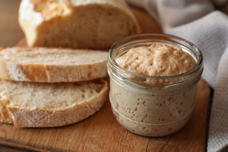 Sourdough starter in glass jar and bread on table, closeupの写真素材