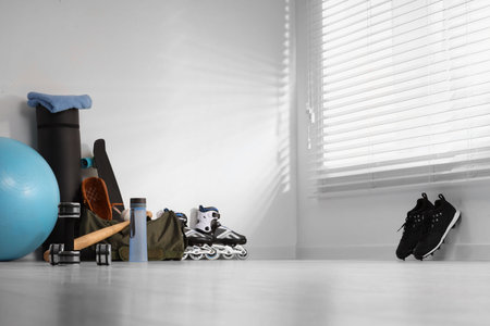 Many different sports equipment near wall indoors, space for text