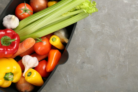 Black pot with fresh vegetables on gray table, top view. Space for textの写真素材