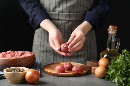Woman making meatball from ground meat at gray table, closeupの写真素材
