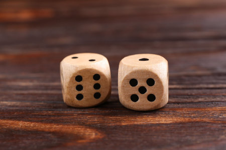 Two game dices on wooden table, closeup