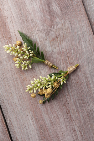 Small stylish boutonnieres on light wooden table, top view