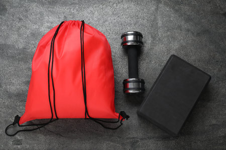 Red drawstring bag, yoga block and dumbbells on dark textured background, flat layの写真素材