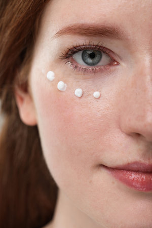 Beautiful woman with freckles and cream on her face, closeupの写真素材