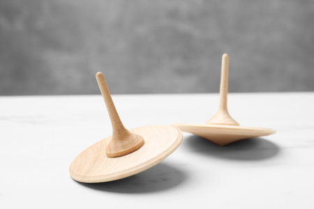 Two spinning tops on white table, closeup