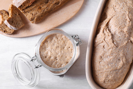 Fresh sourdough starter, dough and bread on light table, flat layの写真素材