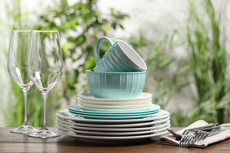 Beautiful ceramic dishware, glasses, cutlery and cup on wooden table outdoors