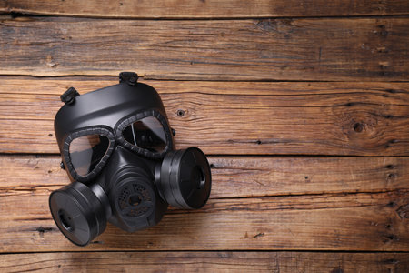 One gas mask on wooden background, top view. Space for text