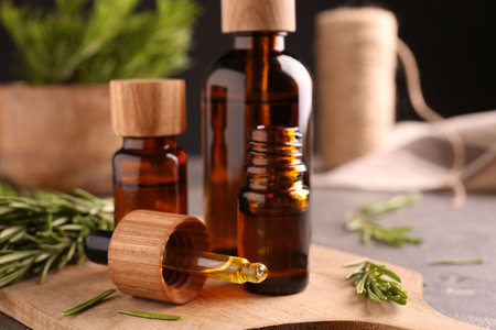 Essential oil in bottles, dropper and rosemary on table, closeupの写真素材