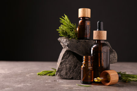 Essential oil in bottles, dropper and rosemary on grey table, space for textの写真素材