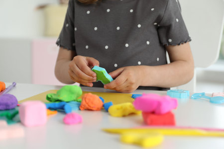 Little girl sculpting with play dough at table indoors, closeupの写真素材