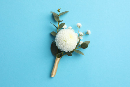 Small stylish boutonniere on light blue background, top view