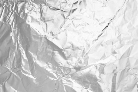 Crumpled silver foil as background, top view