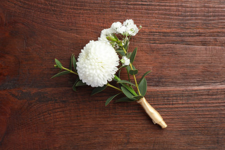 Small stylish boutonniere on wooden table, top view