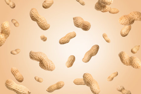 Unpeeled peanuts in the air on beige background