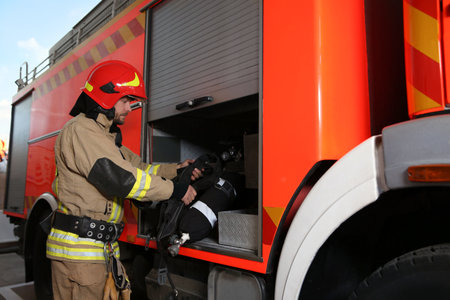 Firefighter in uniform with safety equipment near fire truck at station