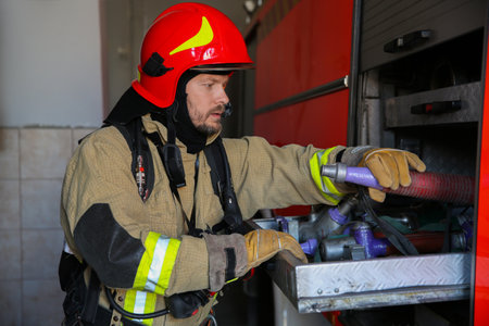 Firefighter in uniform with fire engine equipment at stationの写真素材