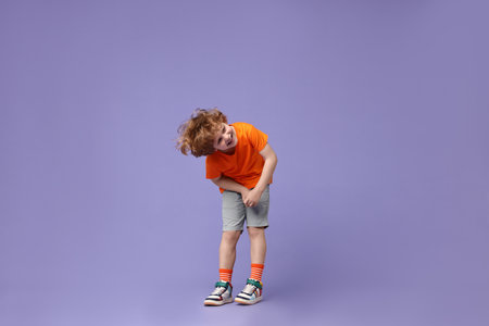 Happy little boy dancing on violet background. Space for textの写真素材