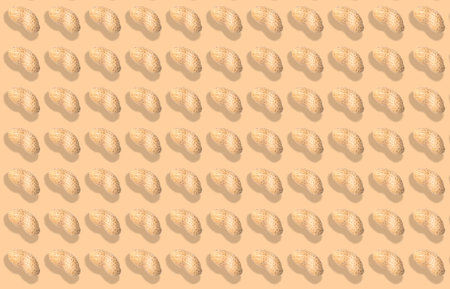 Pattern of unpeeled peanuts on beige background