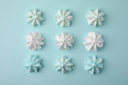 Delicious meringue cookies on light blue background, flat lay
