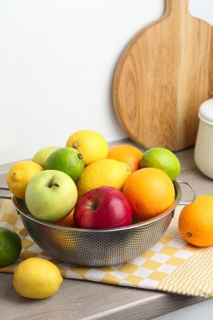 Metal colander with different fruits on countertop in kitchenの写真素材