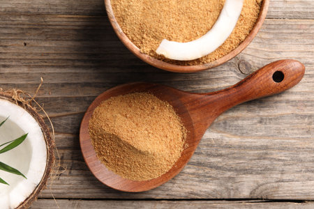 Coconut sugar in bowl, spoon and fruit on wooden table, flat layの写真素材