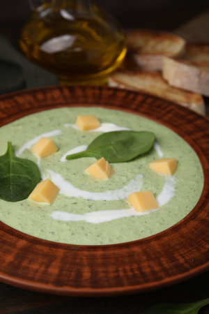 Delicious spinach cream soup with leaves and cheese in bowl on wooden table, closeupの写真素材
