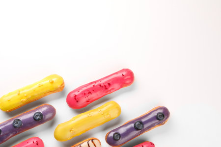 Delicious eclairs covered with glaze on white background, top view