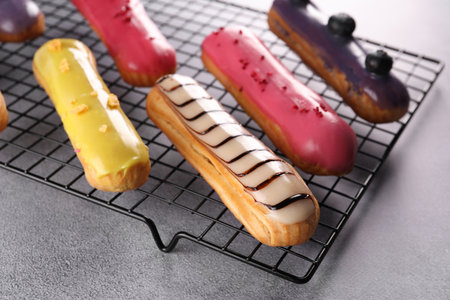 Cooling rack with different tasty glazed eclairs on gray table, closeupの写真素材
