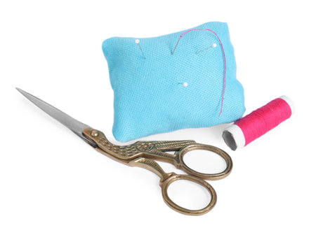 Pincushion with sewing pins, needle, scissors and spool of thread isolated on whiteの写真素材