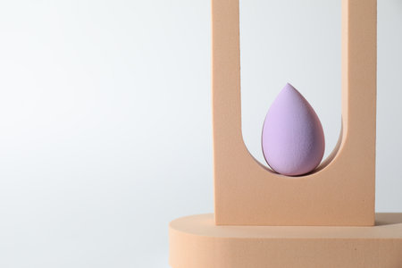 Stylish presentation of violet makeup sponge on white background, space for textの写真素材