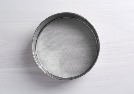One metal sieve on white wooden table, top viewの写真素材