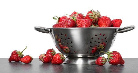 Metal colander with fresh strawberries on gray table against white backgroundの写真素材