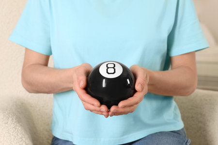 Woman holding magic eight ball indoors, closeupの写真素材