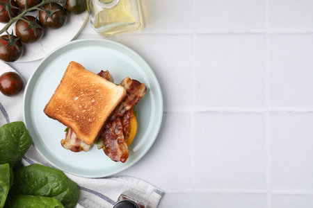 Tasty sandwich with bacon, tomatoes and spices on white tiled table, flat lay. Space for textの写真素材