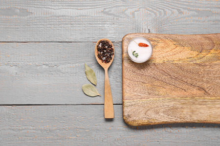 Cutting board, spoon and spices on gray wooden table, flat lay. Space for textの写真素材