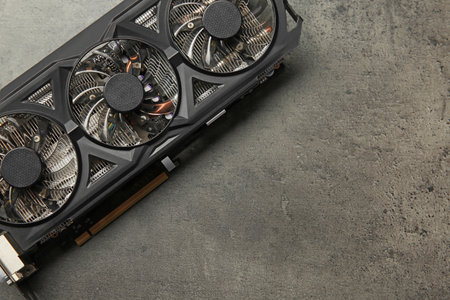 One computer graphics card on gray textured table, top view. Space for text