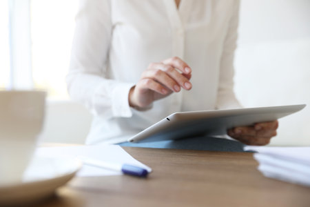 Businesswoman working with modern tablet at wooden table in office, closeupの写真素材