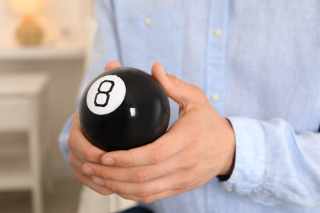 Man holding magic eight ball indoors, closeupの写真素材