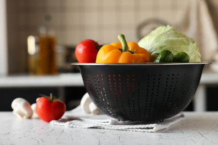 Metal colander with different wet vegetables on white textured tableの写真素材