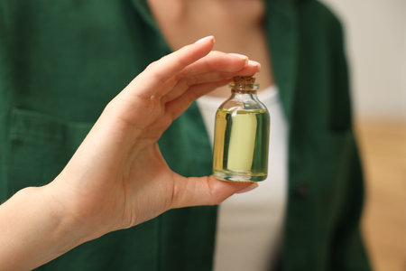 Aromatherapy. Woman with bottle of essential oil on light background, closeup