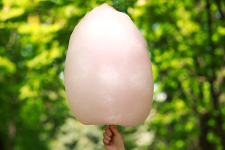 Woman holding sweet cotton candy outdoors, closeup