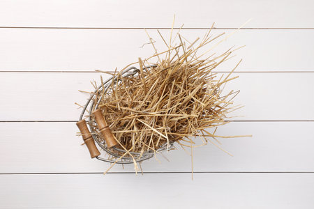 Dried straw in metal basket on white wooden table, top viewの写真素材