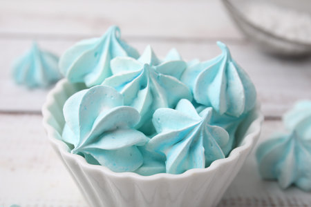 Tasty meringue cookies in bowl on white wooden table, closeupの写真素材