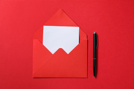 Blank sheet of paper, letter envelope and pen on red background, top view. Space for textの写真素材