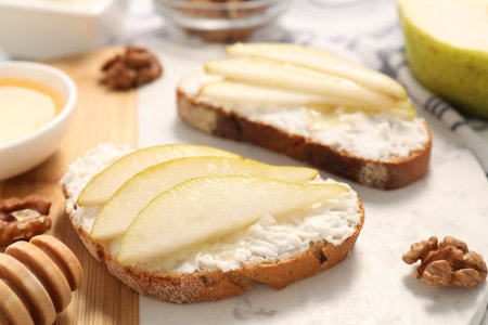 Delicious ricotta bruschettas with pear and walnut on white table, closeupの写真素材