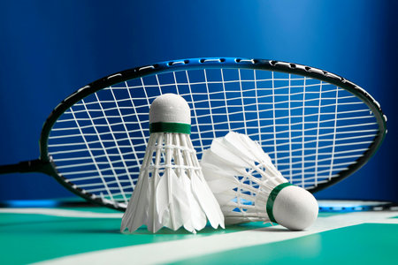 Feather badminton shuttlecocks and racket on green table against blue background, closeupの写真素材