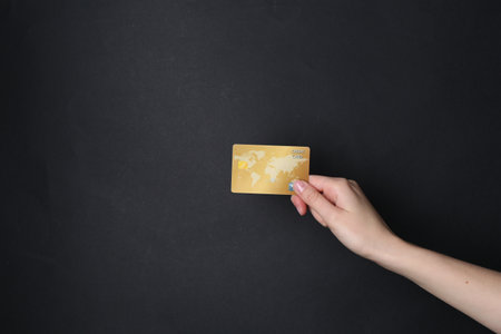 Woman holding credit card on black background, closeupの写真素材