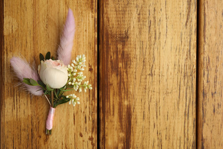 Small stylish boutonniere on wooden table, top view. Space for text